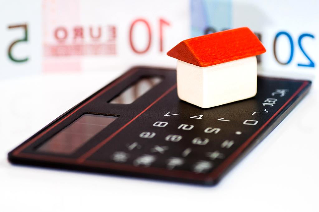Person planning a monthly budget with the 50/30/20 rule using a notebook and calculator